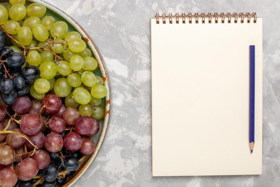 top-view-female-hands-cutting-lemon-with-knife-cornel-berries-grape-cinnamon-cutting-board-pluots-plant-gray-background_141793-52741